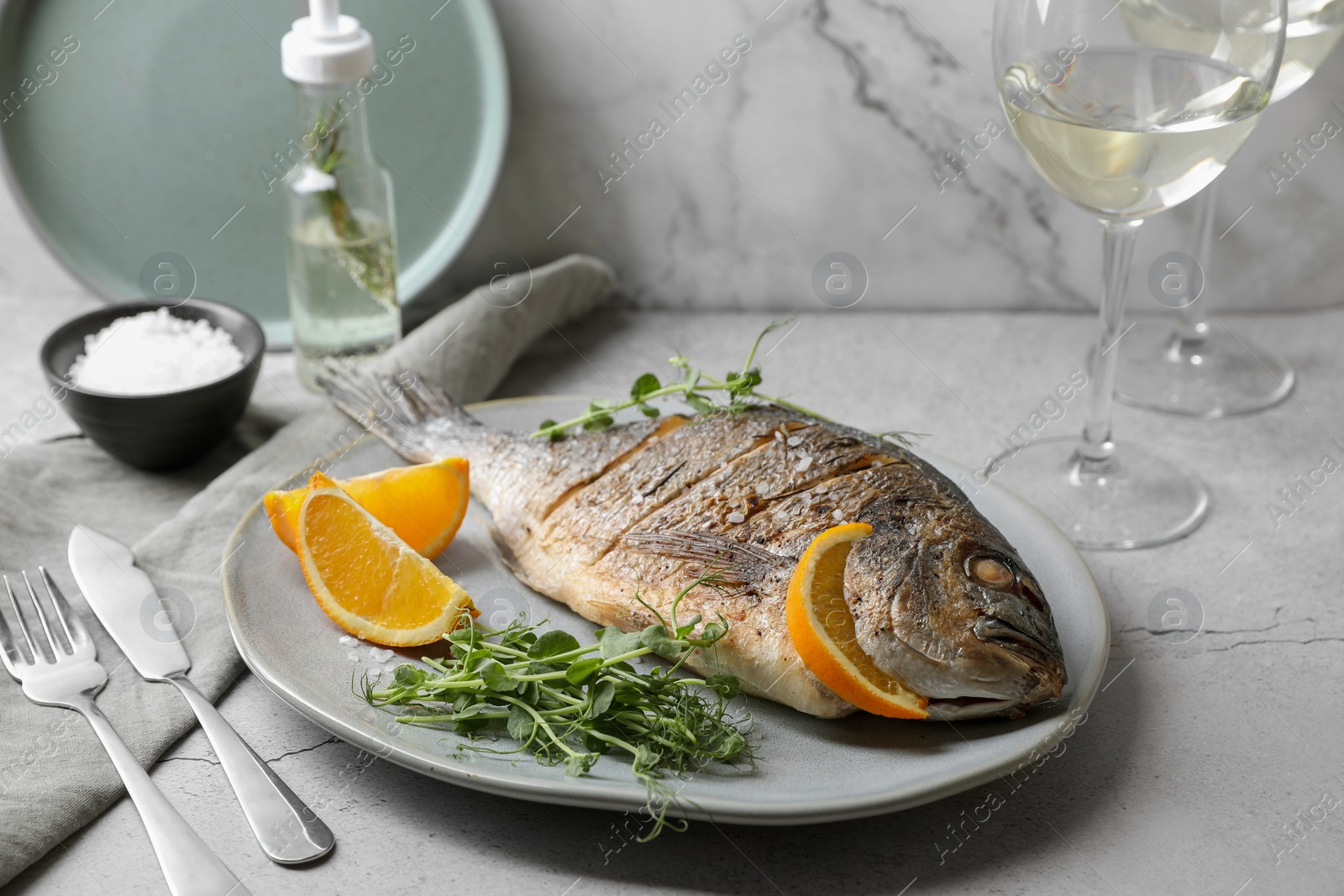 Photo of Seafood. Delicious baked fish served with orange and microgreens on light textured table
