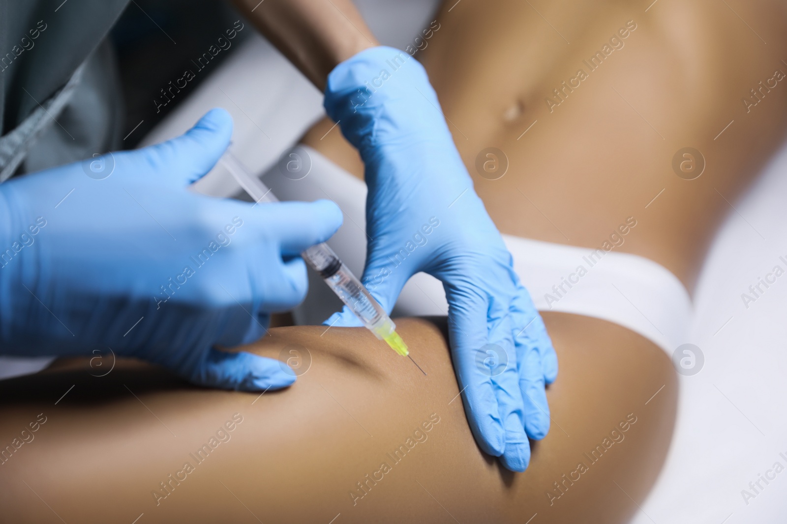 Photo of Young woman getting legs injection in salon, closeup