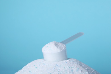 Pile of laundry detergent and measuring scoop against blue background