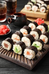 Photo of Tasty sushi rolls served on black wooden table