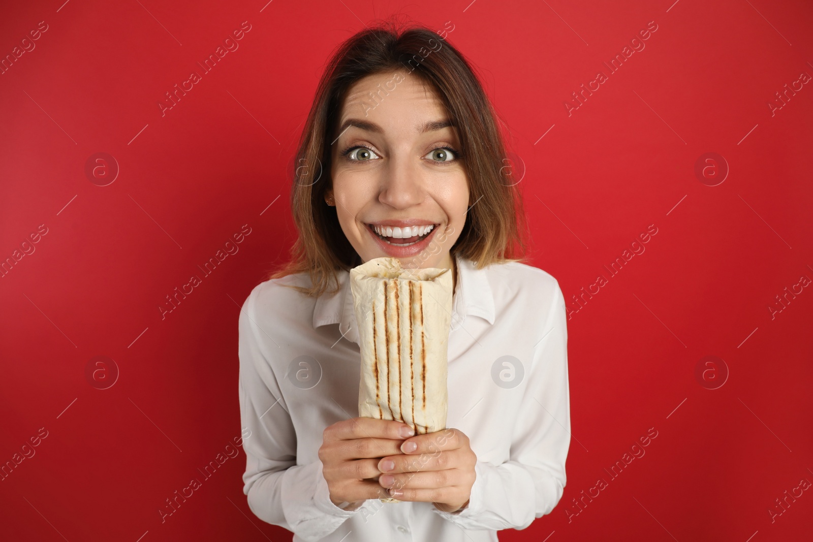 Photo of Emotional young woman with delicious shawarma on red background