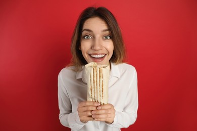 Emotional young woman with delicious shawarma on red background
