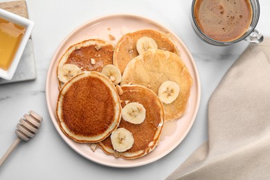 Photo of Tasty pancakes with sliced banana served on white marble table, flat lay