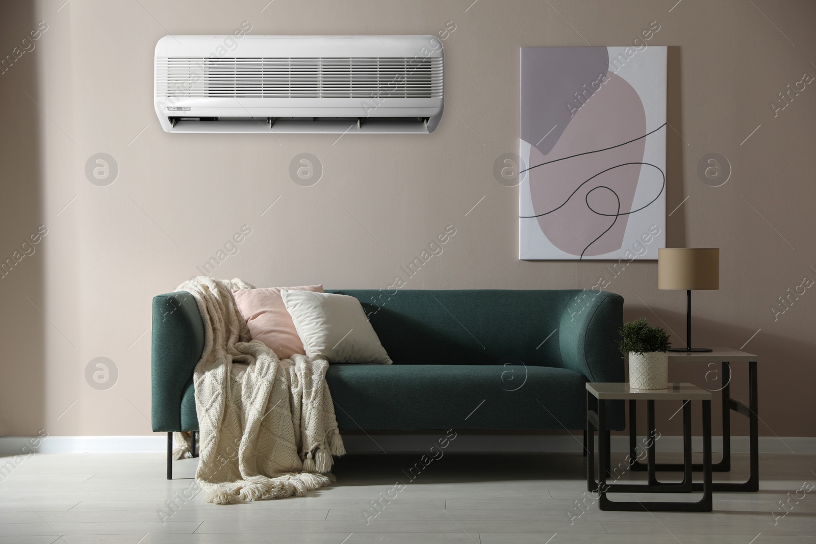 Image of Modern air conditioner on beige wall in room with stylish sofa