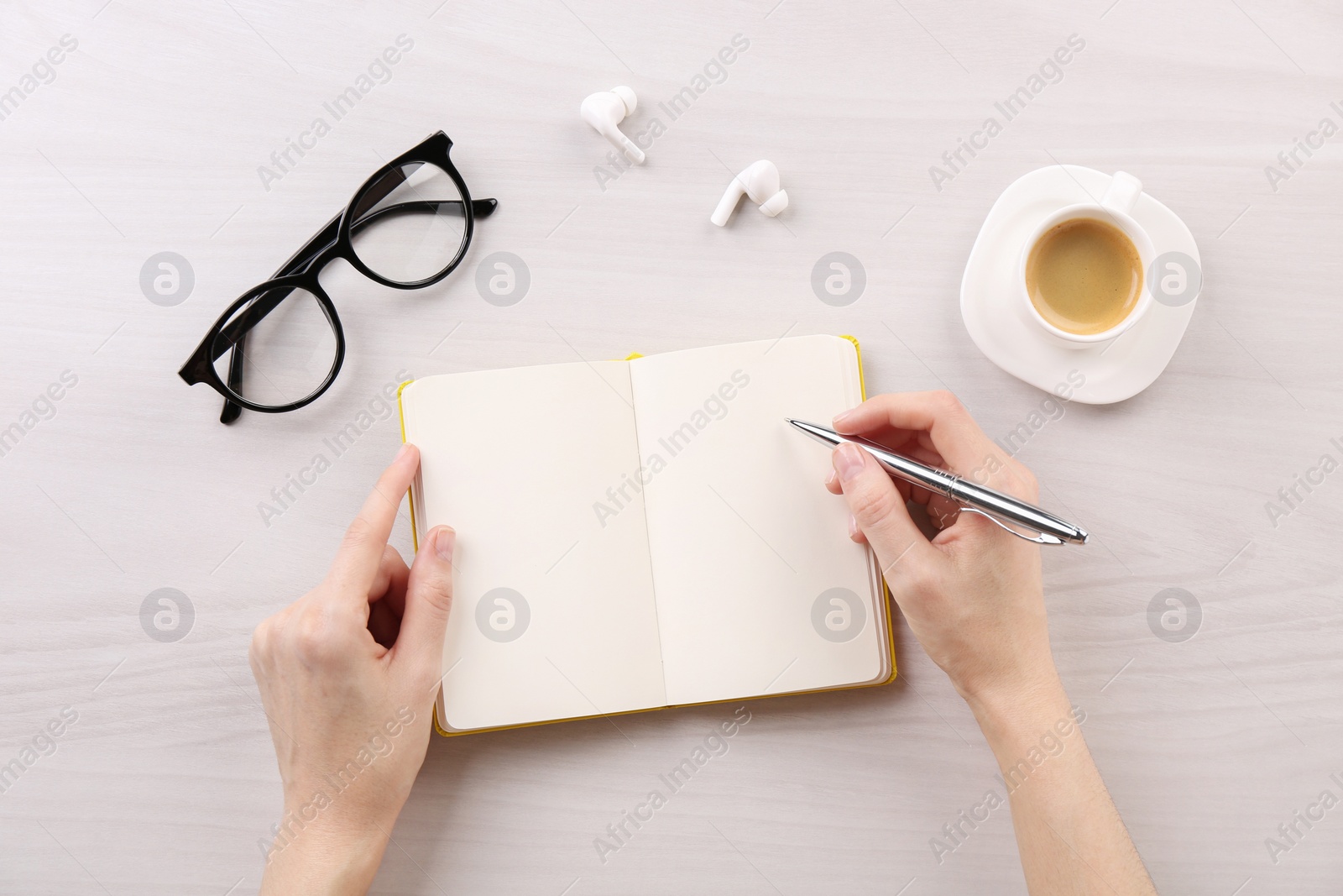 Photo of Woman with notebook and pen at white wooden table, top view. Space for text