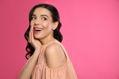 Photo of Portrait of surprised woman on pink background, space for text