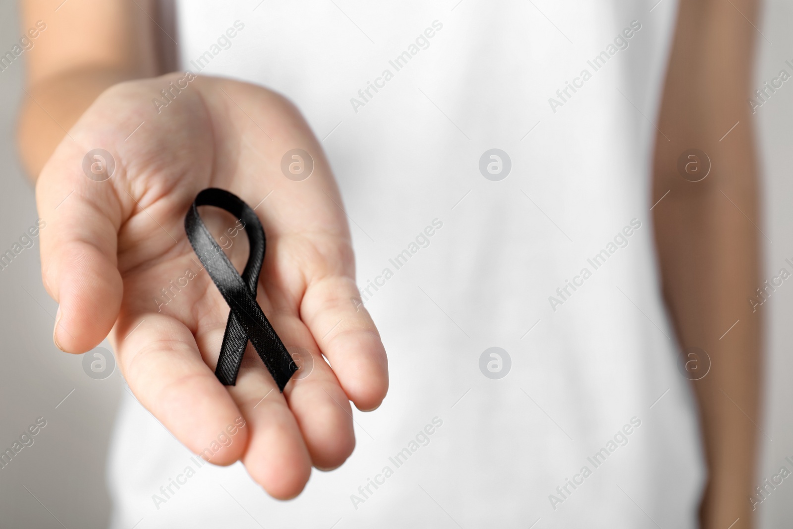 Photo of Young woman holding black ribbon, closeup. Funeral symbol