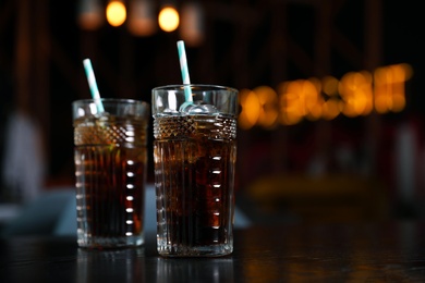 Photo of Glasses with refreshing cola and ice cubes on table indoors. Space for text