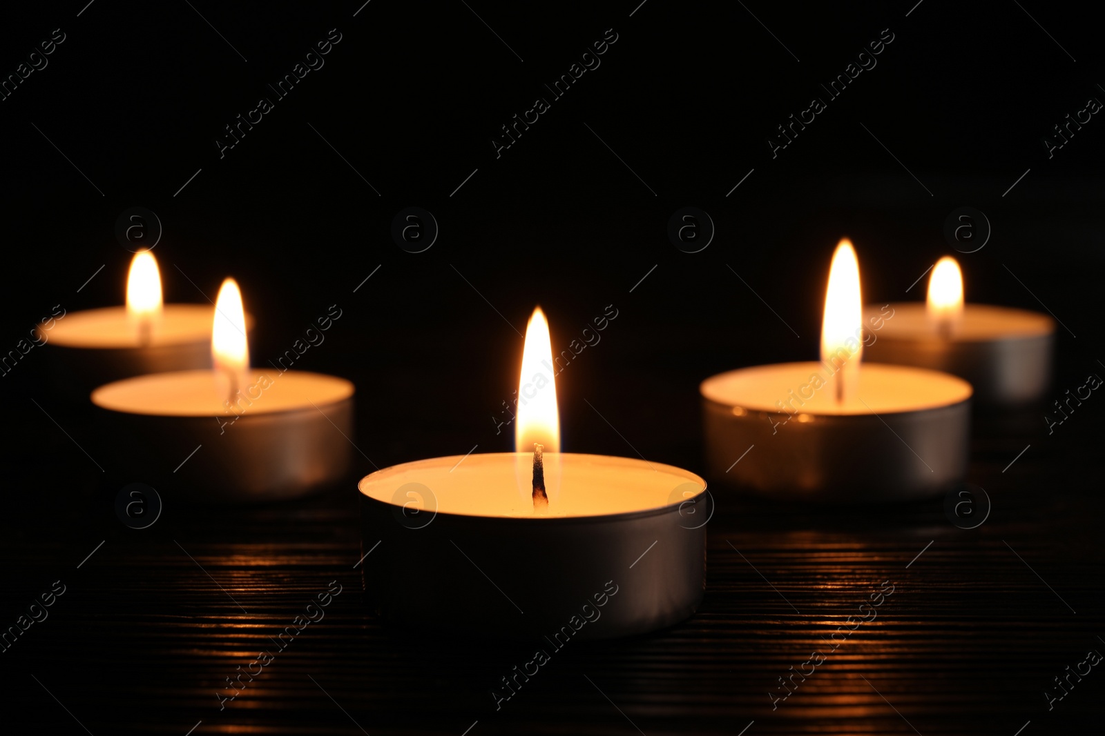 Photo of Burning candles on dark surface. Memory day