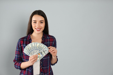 Young woman with money on light grey background. Space for text