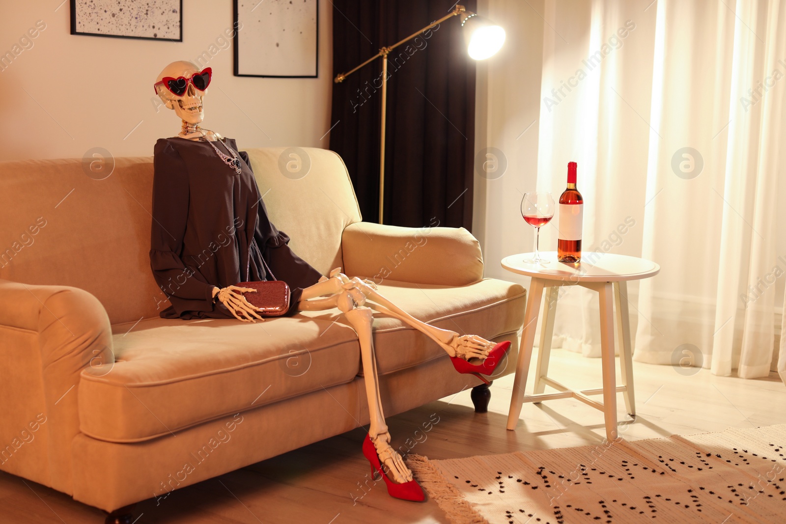 Photo of Skeleton in dress sitting on sofa at home