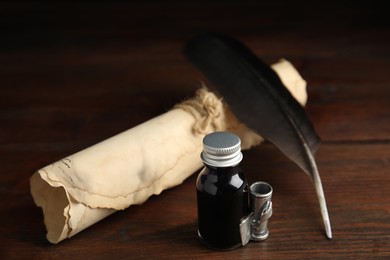 Feather pen, bottle of ink and parchment scroll on wooden table