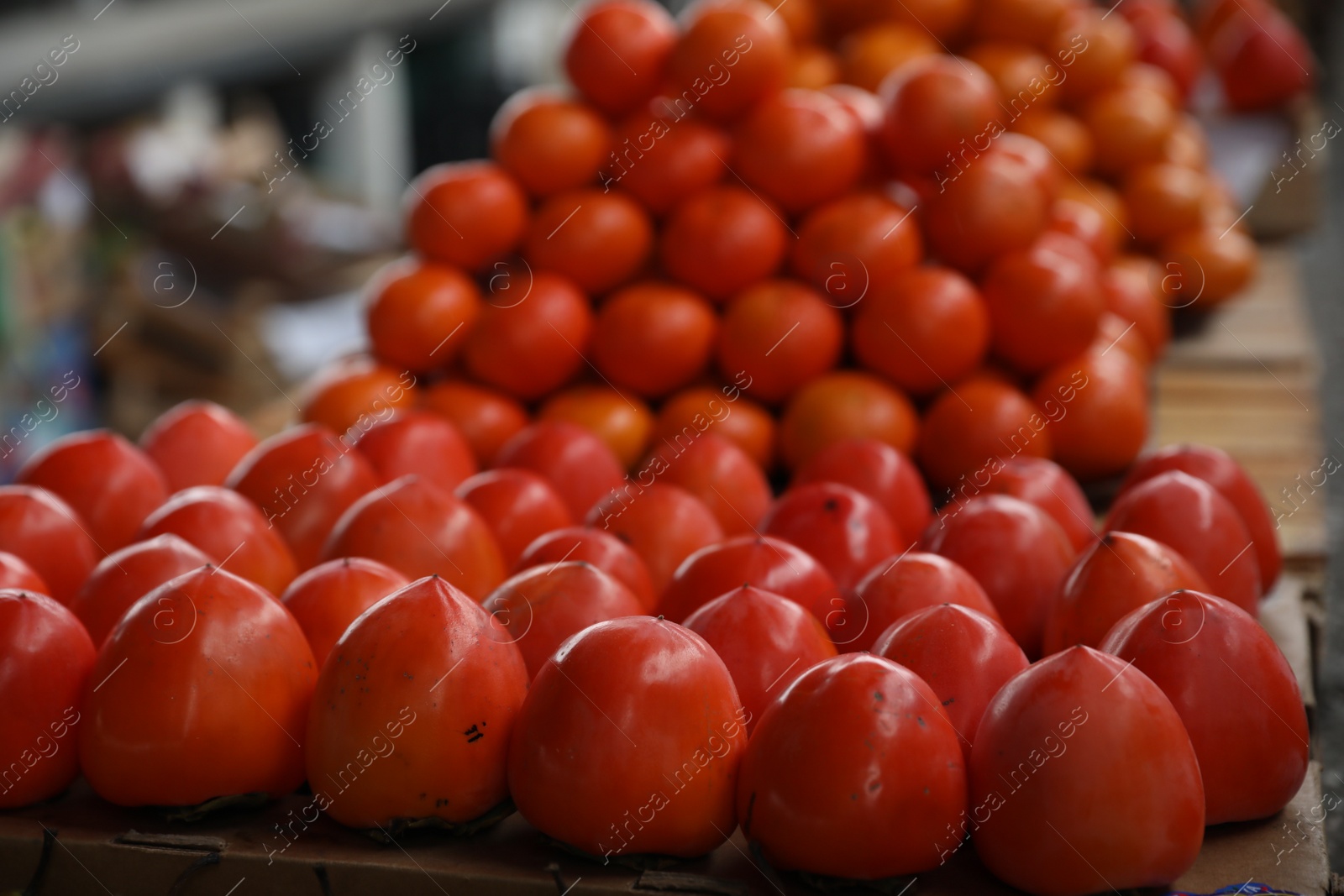 Photo of Fresh ripe persimmon fruit on counter at wholesale market