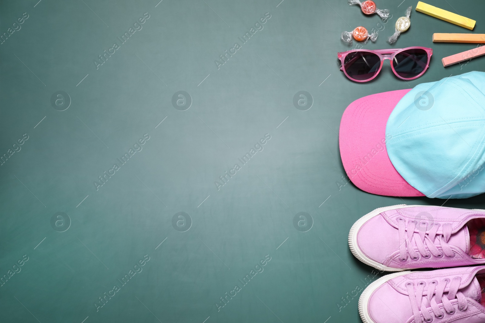 Photo of Flat lay composition with shoes, hat and child accessories on green chalkboard, space for text. School holidays