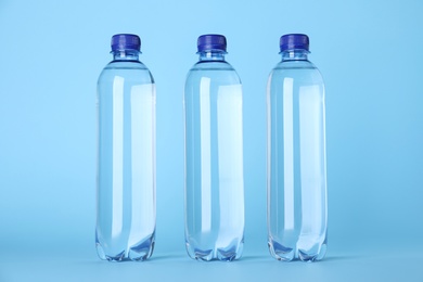 Plastic bottles with water on light blue background