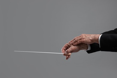 Photo of Professional conductor with baton on grey background, closeup