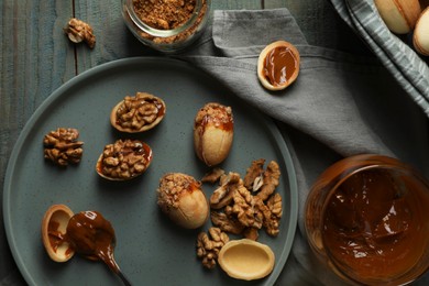 Photo of Freshly baked homemade walnut shaped cookies with nuts and boiled condensed milk on wooden table, flat lay