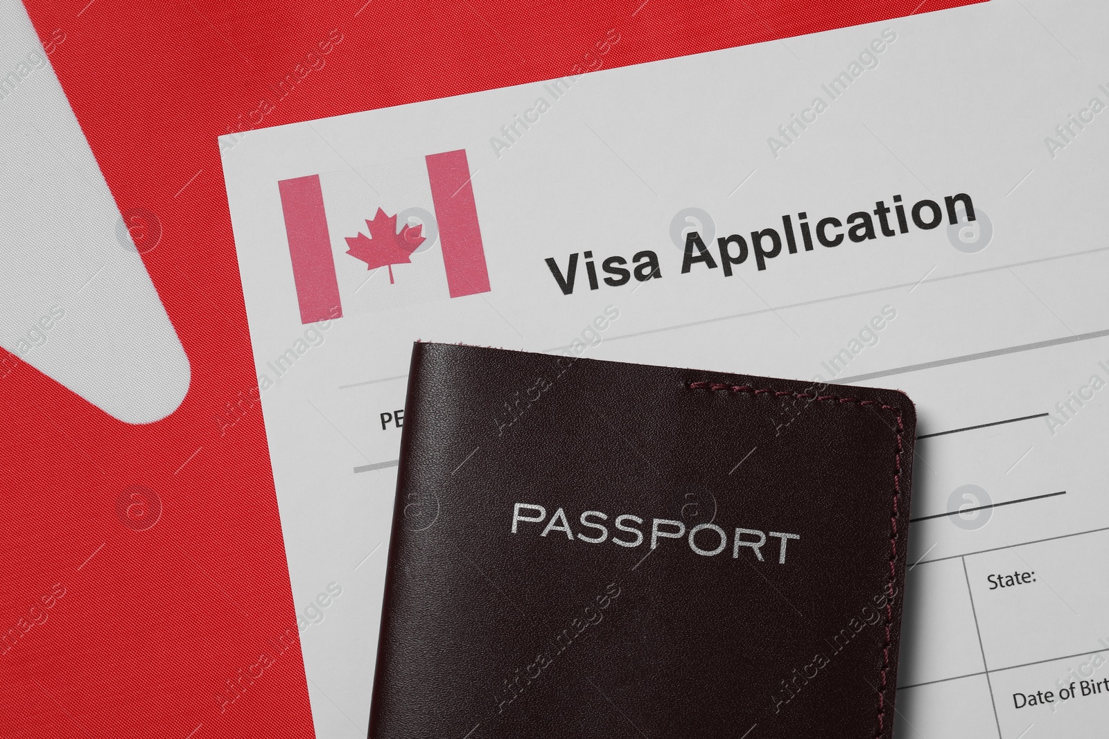 Photo of Immigration to Canada. Visa application form and passport on flag, flat lay