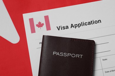 Immigration to Canada. Visa application form and passport on flag, flat lay