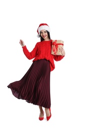 Woman in Santa hat and red sweater holding Christmas gift on white background