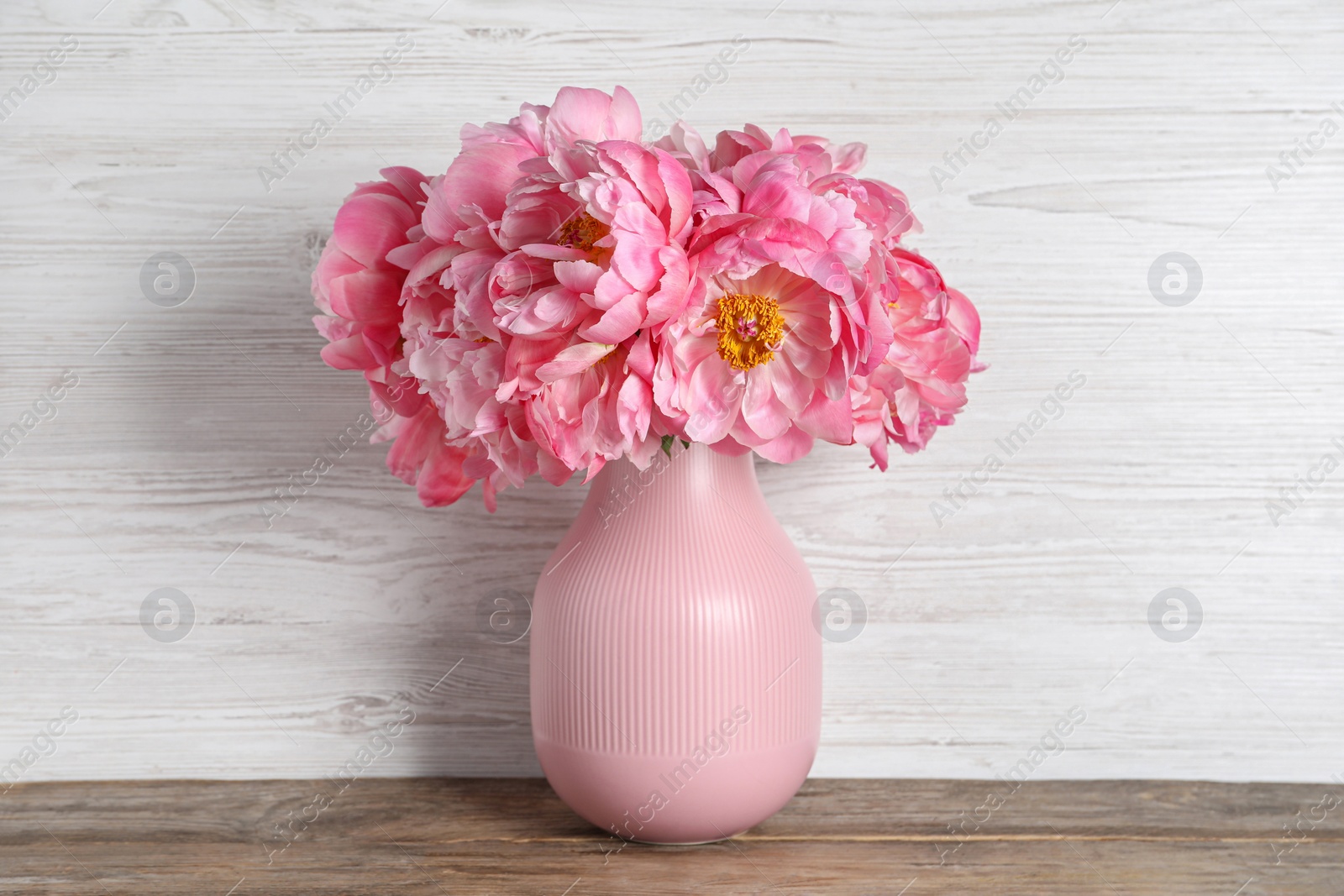 Photo of Beautiful bouquet of pink peonies in vase on wooden table