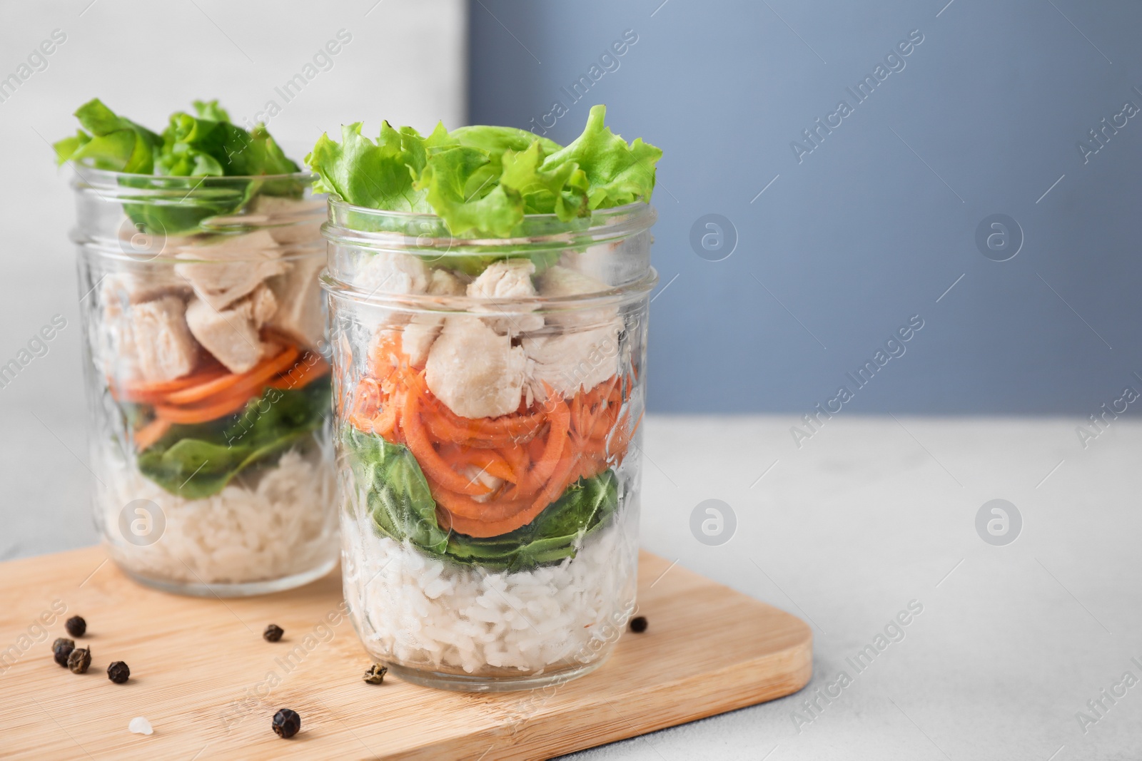 Photo of Healthy salad in glass jars on light table. Space for text