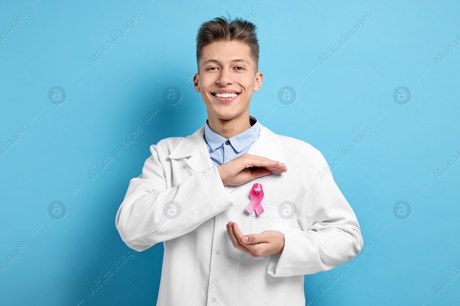 Photo of Mammologist with pink ribbon on light blue background. Breast cancer awareness