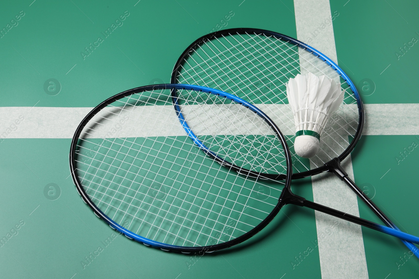 Photo of Feather badminton shuttlecock and rackets on green table, closeup