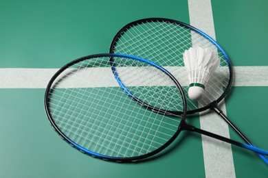 Feather badminton shuttlecock and rackets on green table, closeup