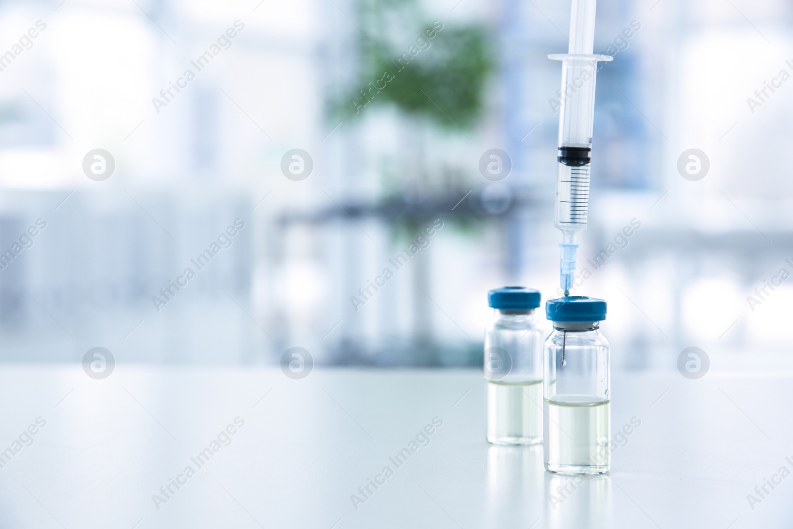 Photo of Vials and syringe with medicine on blurred background. Vaccination concept