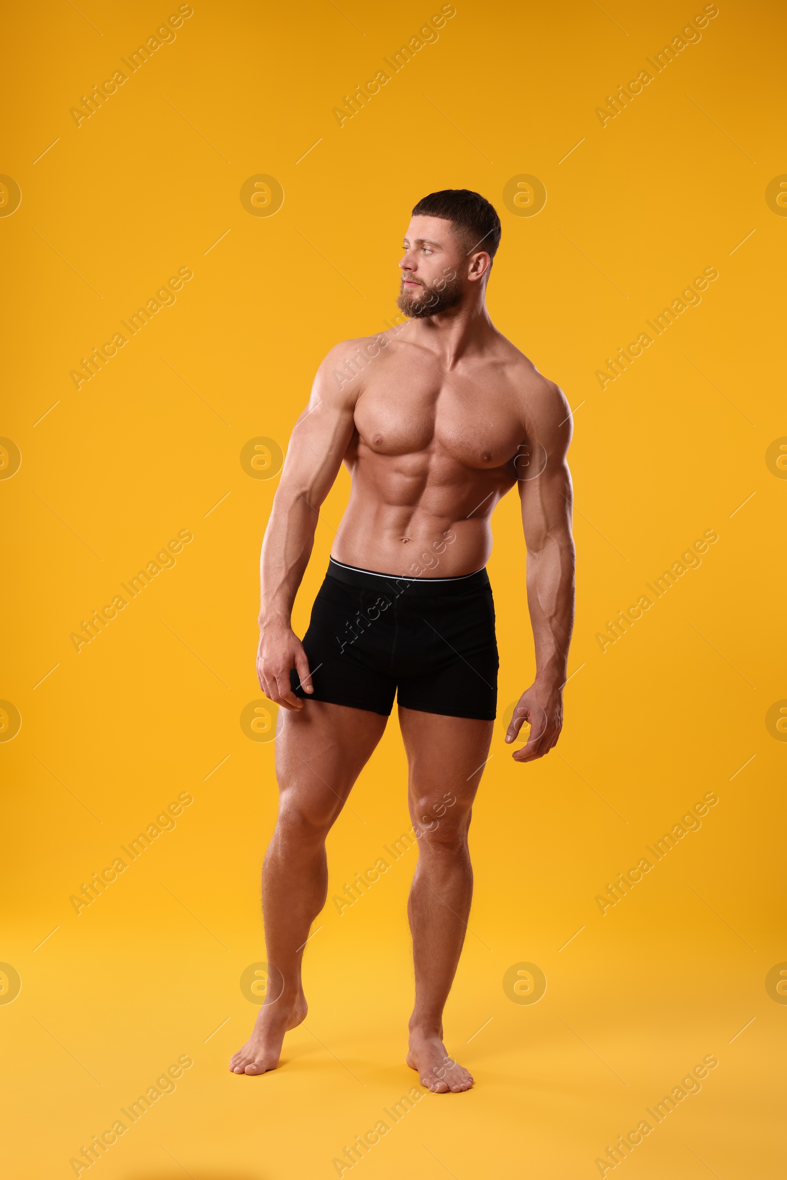 Photo of Young man is stylish black underwear on orange background