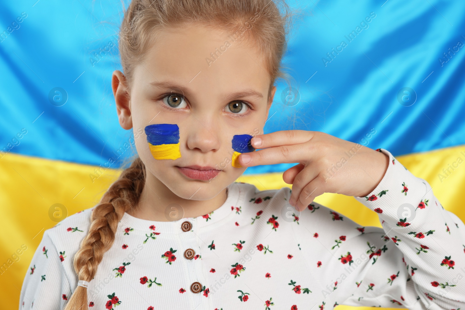 Photo of Little girl with face paint near Ukrainian flag