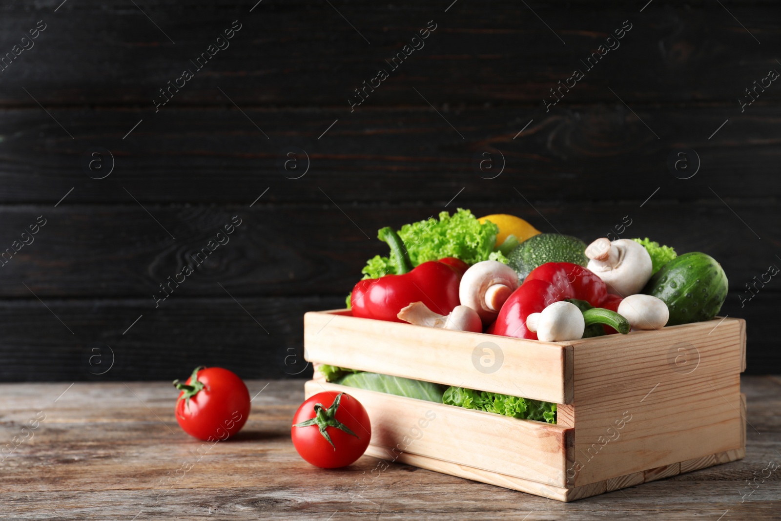 Photo of Wooden crate full of fresh ripe vegetables on table. Space for text