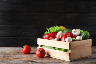 Photo of Wooden crate full of fresh ripe vegetables on table. Space for text