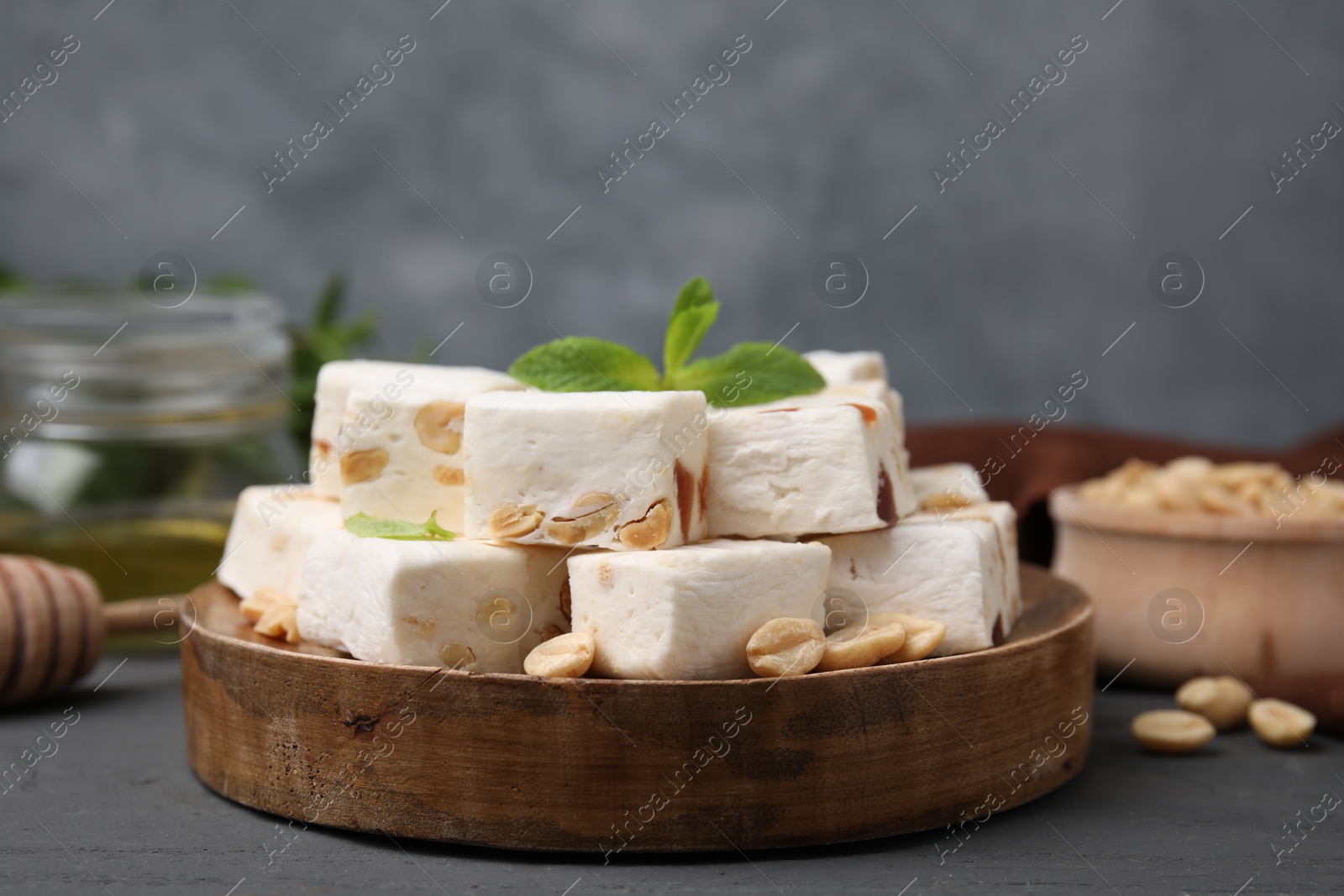 Photo of Pieces of delicious nougat and nuts on wooden board, closeup