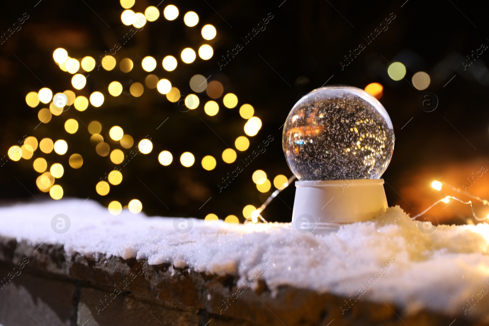 Photo of Snow globe and blurred Christmas lights on background. Space for text