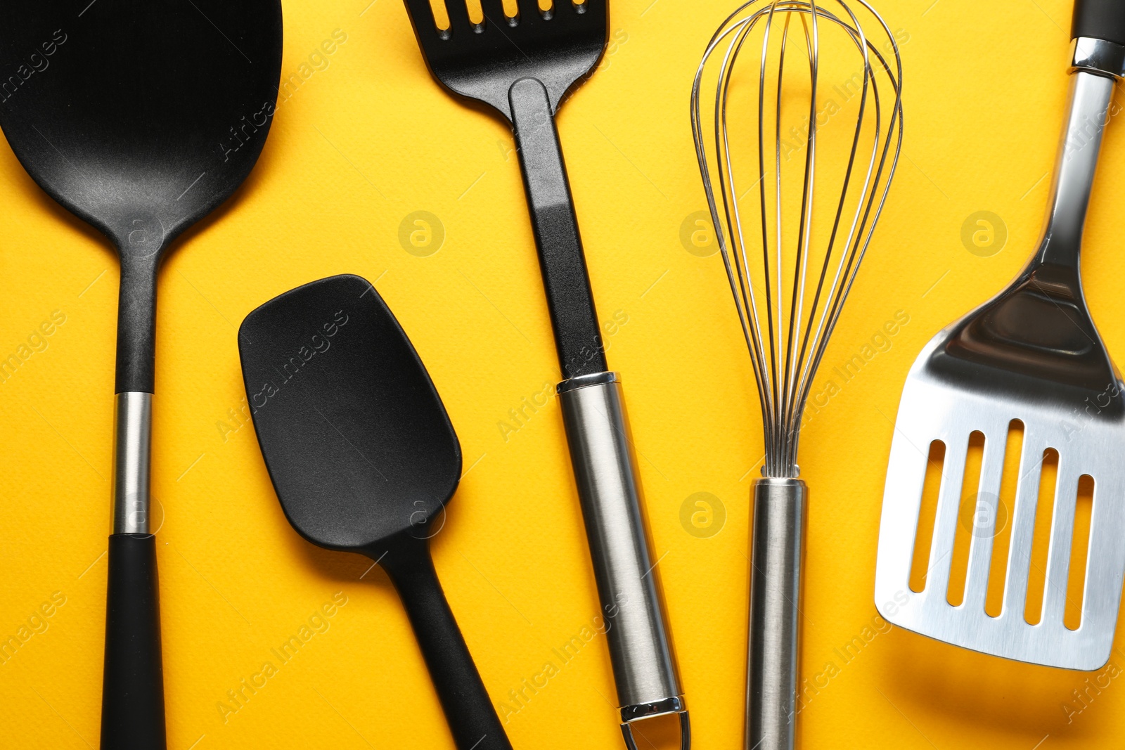 Photo of Different spatulas and whisk on orange background, flat lay