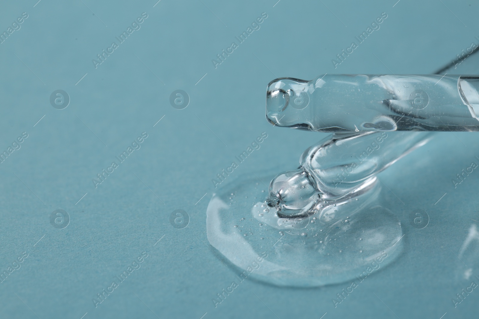 Photo of Dripping cosmetic serum from pipettes onto light blue background, macro view. Space for text