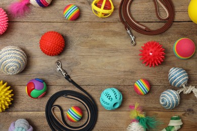 Photo of Flat lay composition with pet leashes and toys on wooden background, space for text