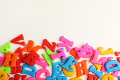 Photo of Many colorful magnetic letters on white background, flat lay. Space for text