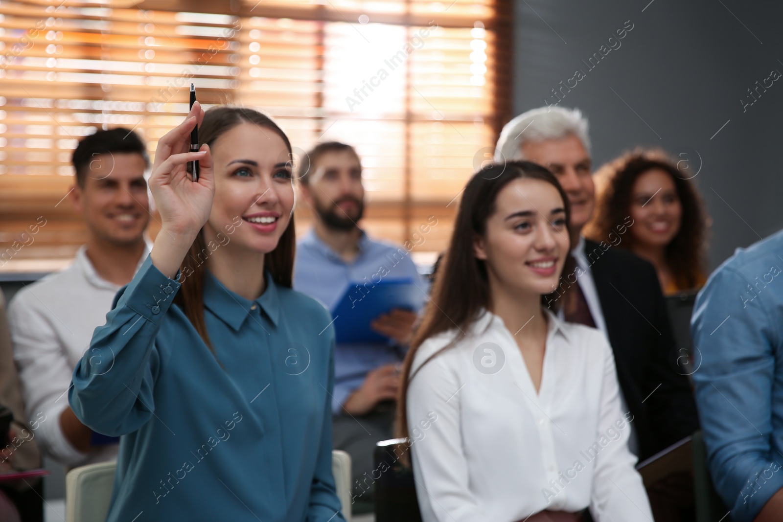 Photo of Woman raising hand to ask question at seminar in office, closeup