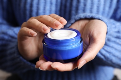 Photo of Woman holding jar of moisturizing cream, closeup. Winter skin care cosmetic