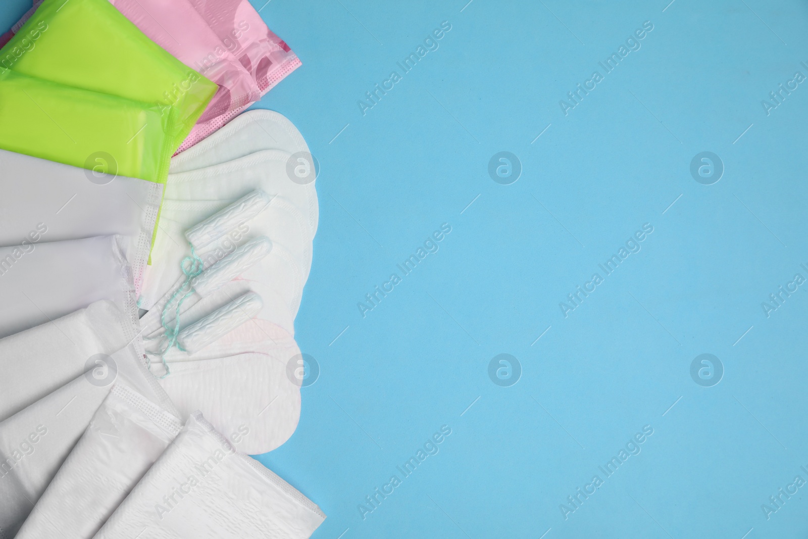 Photo of Menstrual pads, tampons and pantyliners on light blue background, flat lay. Space for text