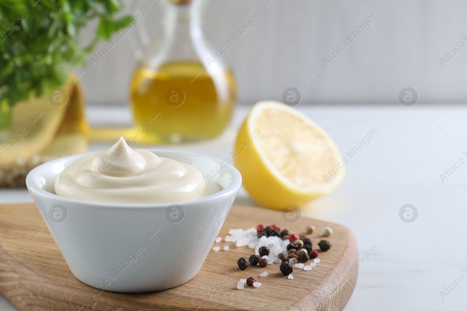 Photo of Tasty mayonnaise sauce in bowl and spices on white table, closeup. Space for text