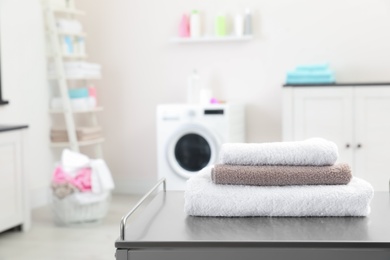 Stack of towels on table against blurred background, space for text