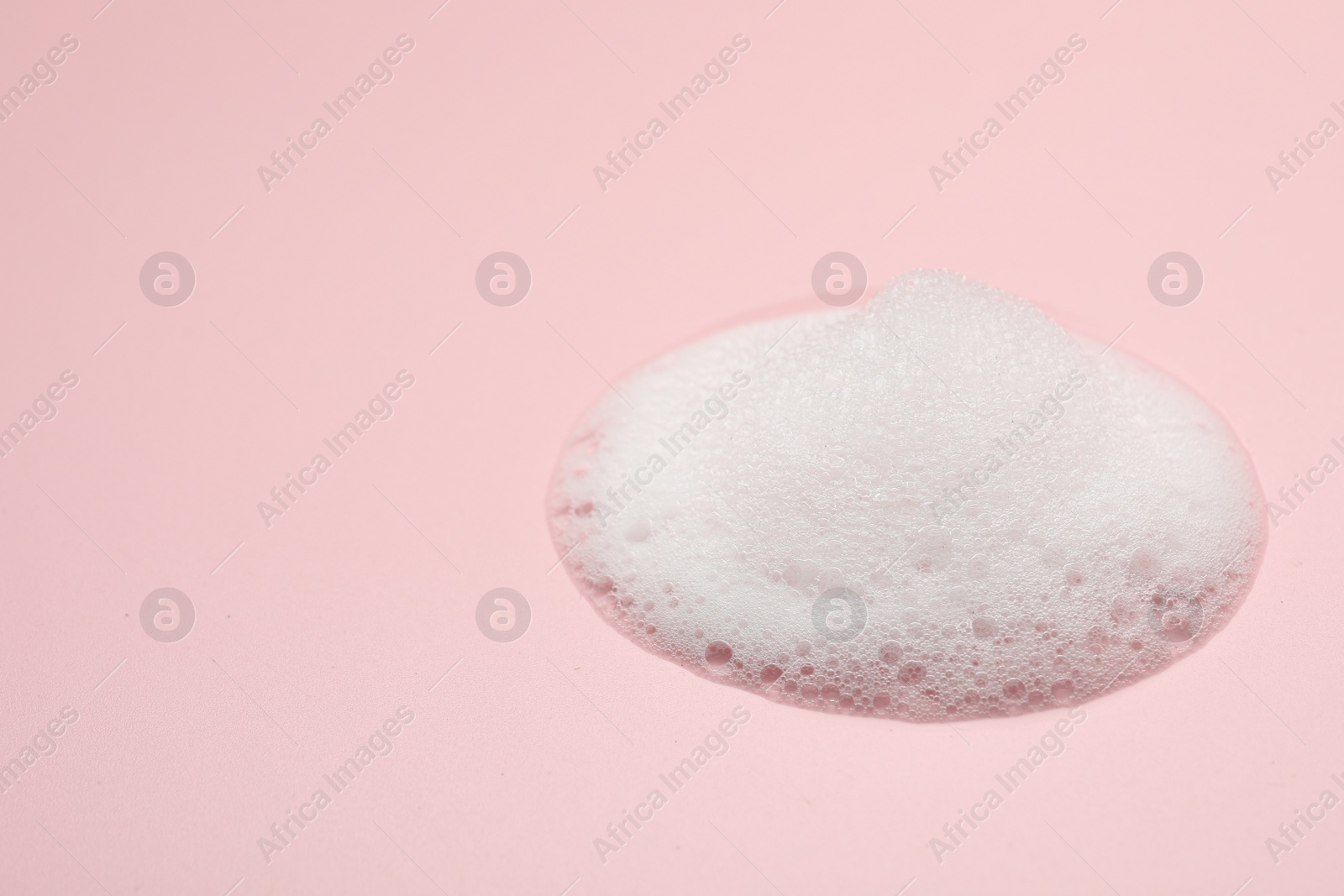 Photo of Drop of fluffy soap foam on pink background