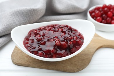 Photo of Fresh cranberry sauce in bowl on white wooden table, closeup