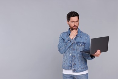 Photo of Confused man with laptop on light grey background. Space for text