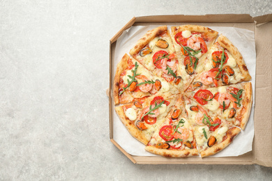 Delicious seafood pizza in box on light grey table, top view. Space for text