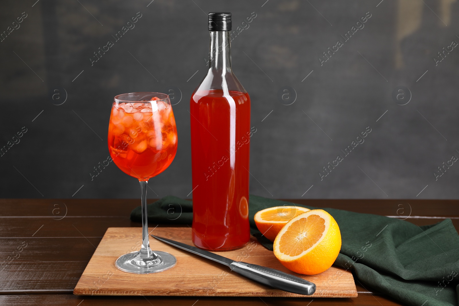 Photo of Aperol spritz cocktail and ice cubes in glass and bottle on wooden table